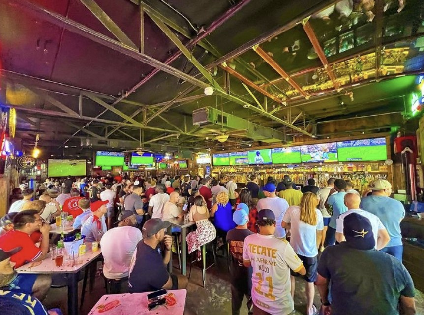A crowd at a bar watching sports on TVs
