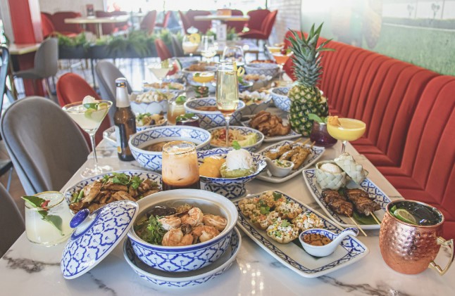 A table covered in Thai dishes at a restaurant.